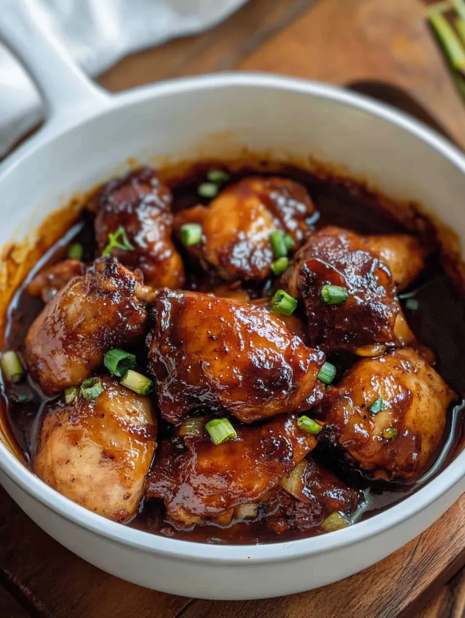 Eine Schüssel Hühnchen mit grüner Garnierung.