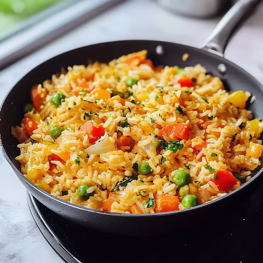 Eine Pfanne mit buntem, gebratenem Reis, der mit Erbsen, Paprika und Kräutern garniert ist.
