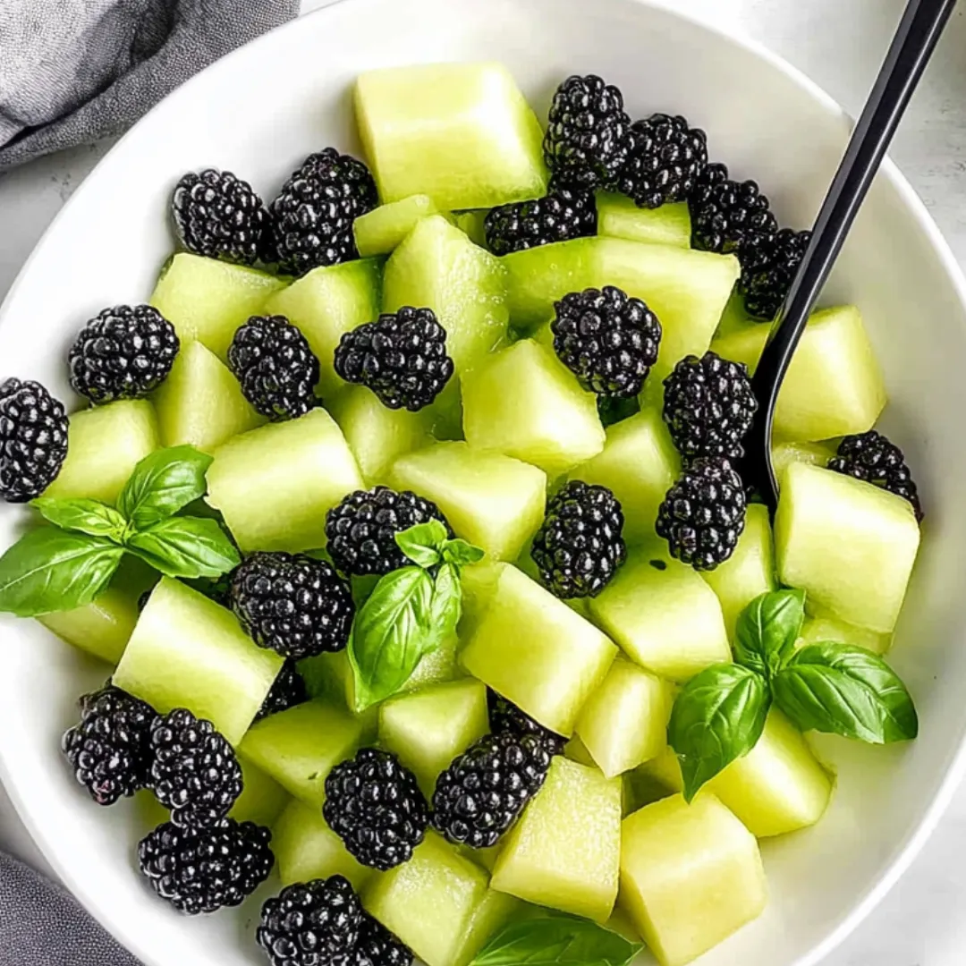 Eine Schale voller Früchte mit Brombeeren, grünen Äpfeln und frischer Minze.