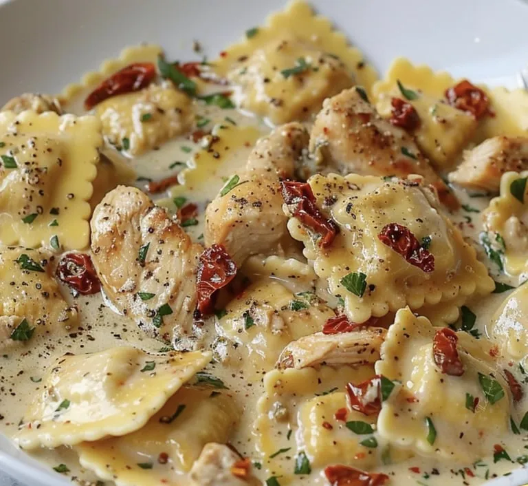 Nudelgericht mit Hähnchen und roten Paprika auf einem Teller.