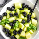 Eine Schale voller Früchte mit Brombeeren, grünen Äpfeln und frischer Minze.