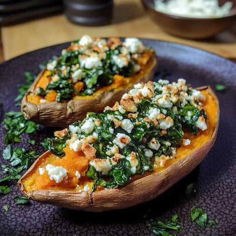 Gefüllte Süßkartoffeln mit Feta, Spinat und Pinienkernen auf einem Teller serviert.
