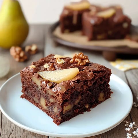 Ein Teller mit einem saftigen Brownies mit Birnenstücken und Walnüssen.