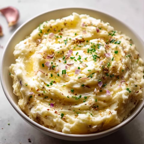 Eine Schale mit Kartoffelbrei, garniert mit grünen Kräutern.