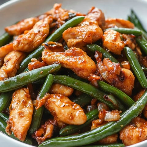 Ein Teller mit Huhn und grünen Bohnen.