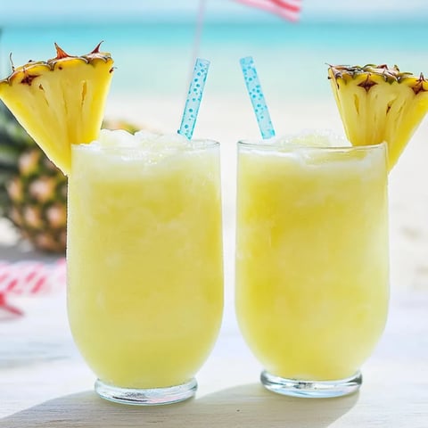 Zwei Gläser Ananassaft auf einem Tisch.