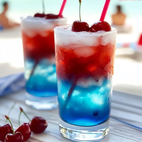 Zwei Gläser Kirschlimonade und Kirschen daneben.