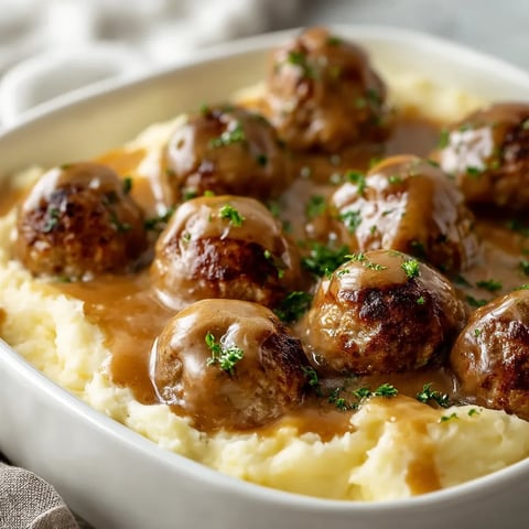 Eine Schale mit Frikadellen und Bratensauce.