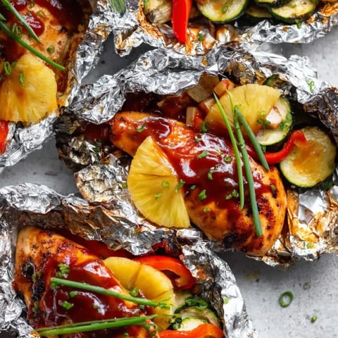 Zartes Hähnchen mit Ananasstücken, frisch auf Alufolie angerichtet.