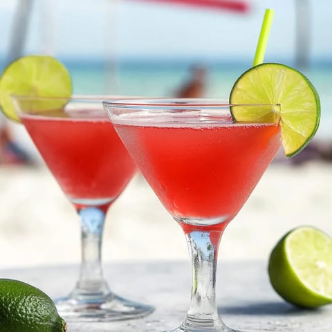 Zwei Gläser mit pinkem Drink und Limetten an der Seite.