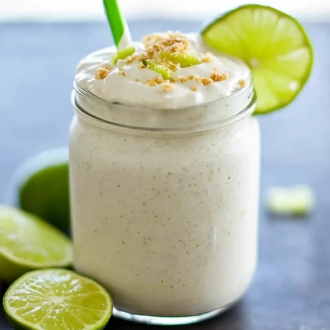 Ein Glas mit weißer Creme und Limettenschnitz oben drauf.