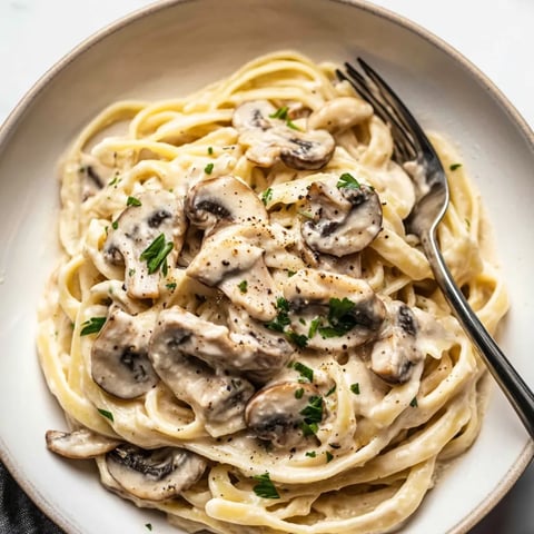 Teller mit Pasta, Pilzen und frischen Kräutern.