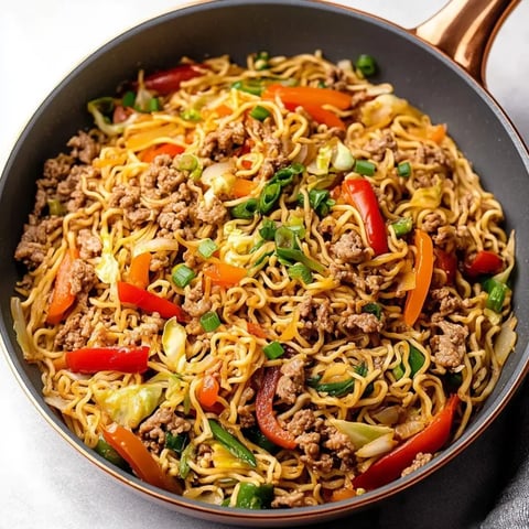 Schüssel voller Nudeln, Fleisch und buntem Gemüse.