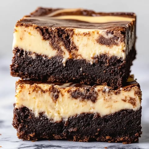 Quadratisches Schokostück mit weißer Cremeschicht oben drauf.