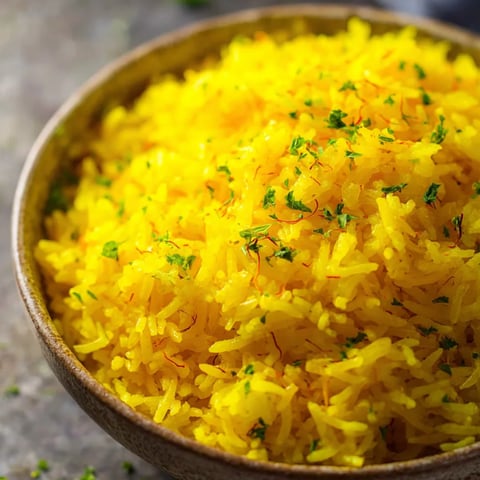 Eine Schüssel gelber Reis mit grünen Kräutern obendrauf.